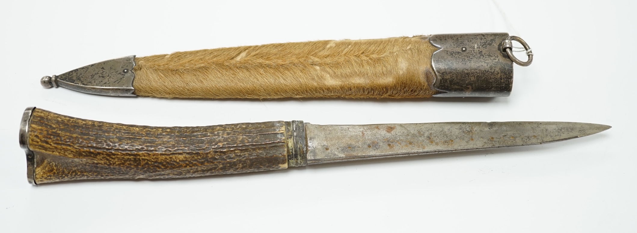 A Scottish dagger c.1900 with silvered mounts, including old initials engraved to pommel and applied to top mount, with deer skin covered sheath and antler grip, blade 19cm.